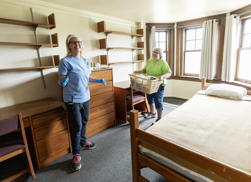 Custodians clean a dorm room in preparation for reunion