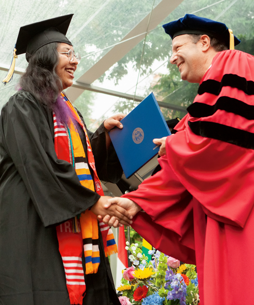 Steve Poskanzer presents a graduate with their diploma at commencement ceremony.